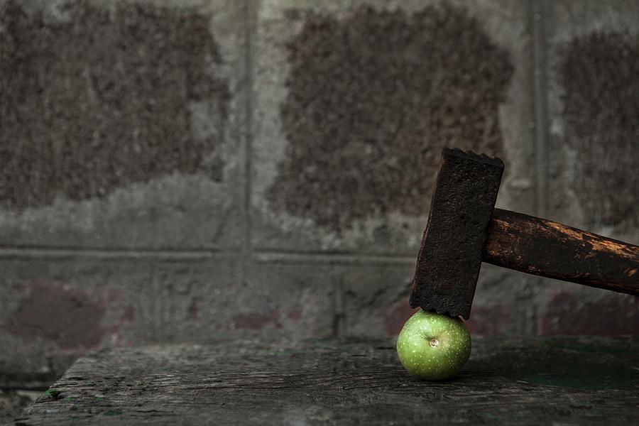 A Green Walnut With A Hammer On A Wooden Table Photograph by Nika Moskalenko