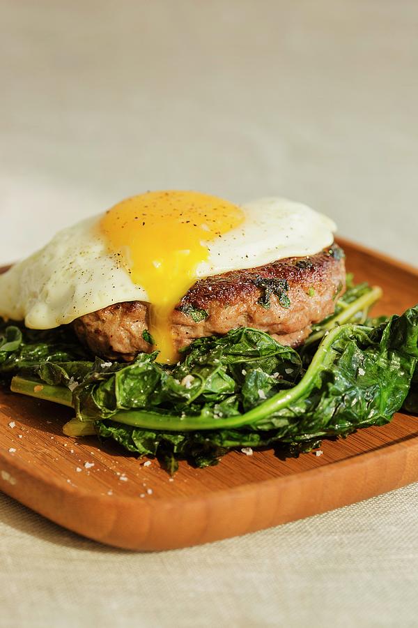 A Grilled Lamb Burger Topped With A Fried Egg And Served With Sauted Kale Photograph by Colin Cooke