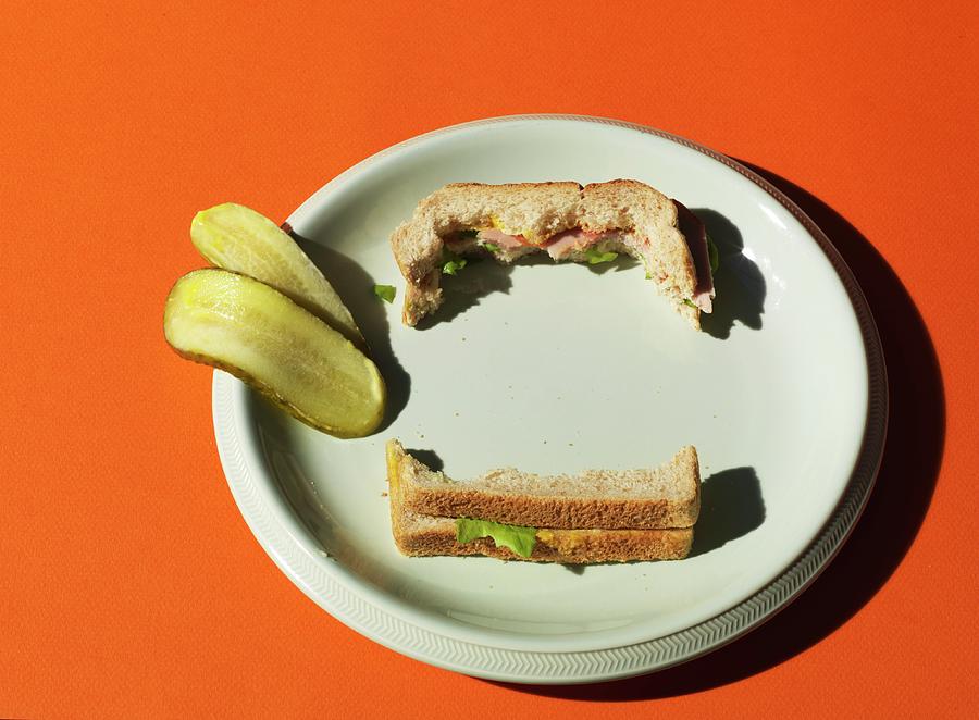 A Half-eaten New York Deli Sandwich And Sliced Gherkin On A White Plate Photograph by Hugh Johnson