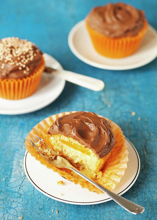A Half-eaten Vanilla Cupcake With Orange And Chocolate Cream Photograph by Jane Saunders