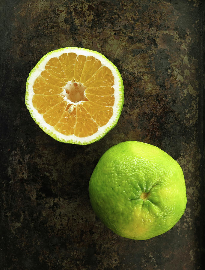 A Halved And Whole Ugli Fruit On A Dark Surface Photograph by Emily Brooke Sandor