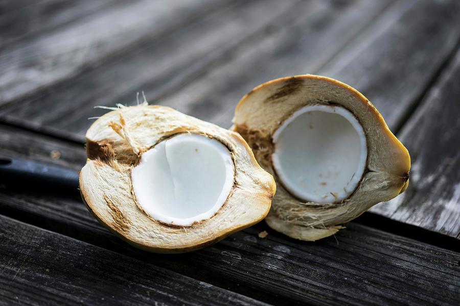 A Halved Coconut On A Wooden Surface Photograph by Alena Haurylik