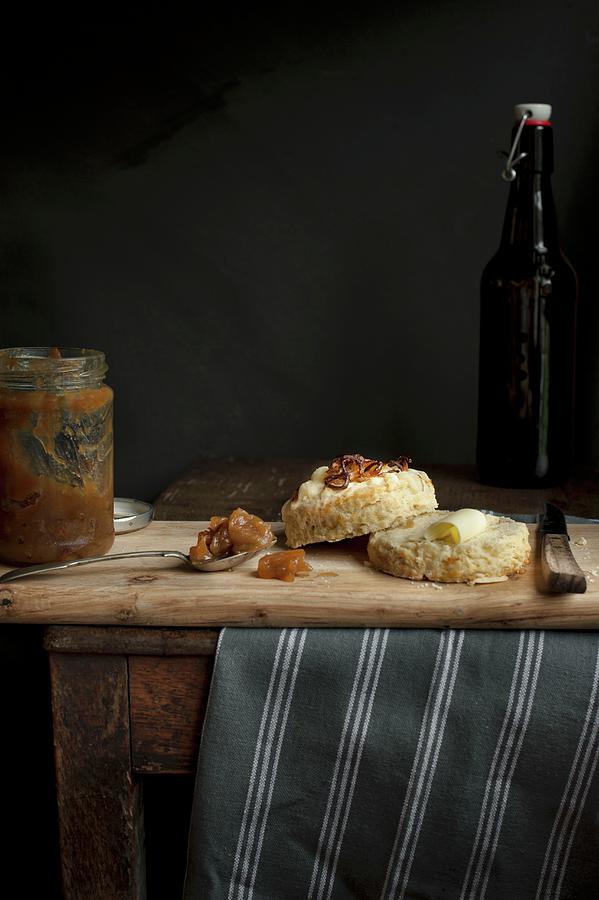 A Halved Onion And Cheese Scone, With Butter, On A Wooden Board With A Jar Of Apple Chutney Photograph by Magdalena Hendey