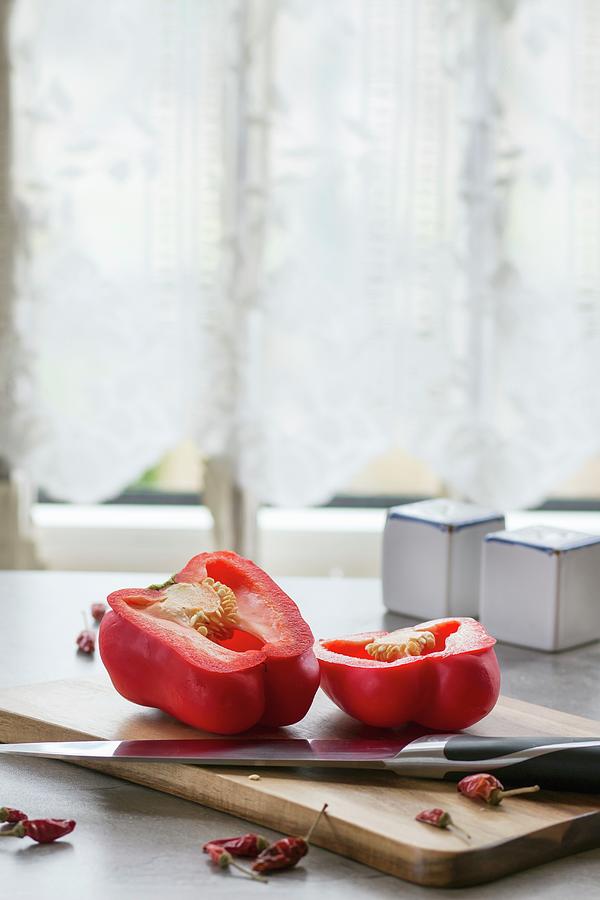 A Halved Pepper And Dried Chilli Peppers On A Kitchen Table Photograph by Natasha Breen