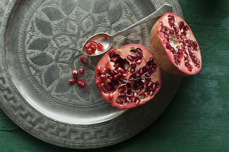 A Halved Pomegranate On A Decorative Metal Plate Photograph by Achim Sass