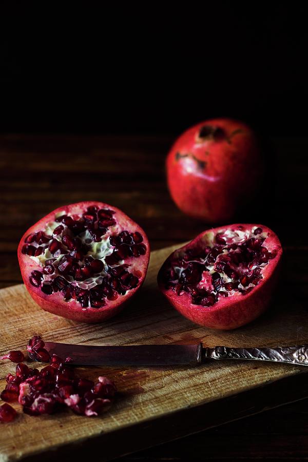 A Halved Pomegranate On A Wooden Chopping Board Photograph by Vernica Orti