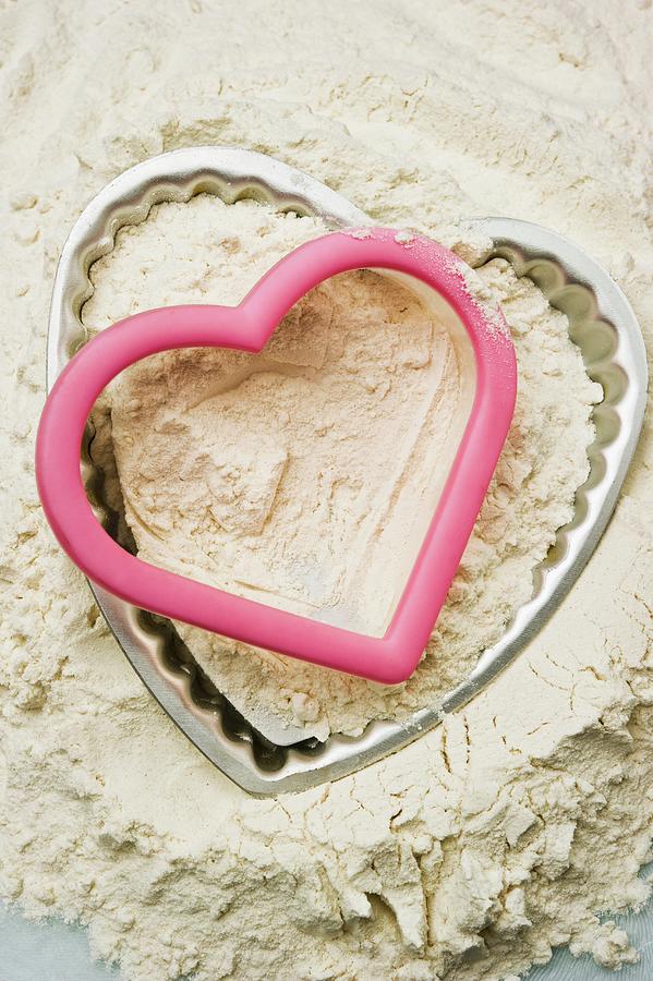 A Heart-shaped Baking Tin And Cutter In A Mound Of Flour Photograph by Linda Burgess