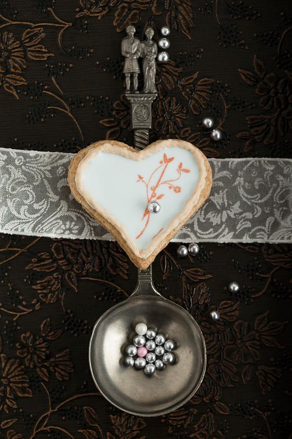 A Heart-shaped Biscuit With An Egg White Glaze And A Stamped Motif On A Spoon With A Bridal Couple Photograph by Mandy Reschke