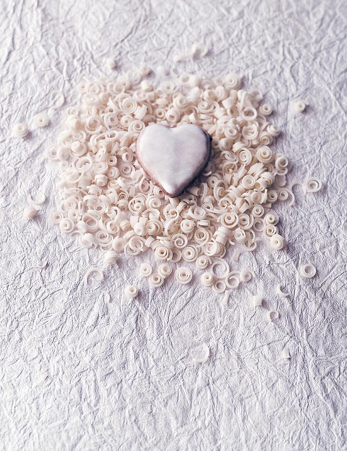 A Heart-shaped Biscuit With Curls Of White Chocolate On A Piece Of White Paper Photograph by Julian Winkhaus