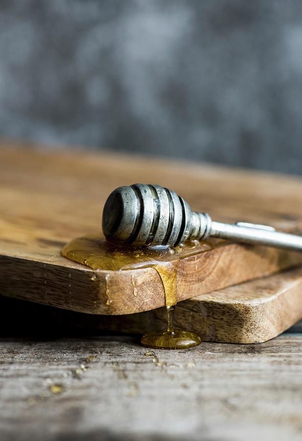 A Honey Dipper With Honey On A Wooden Board Photograph by Hein Van Tonder