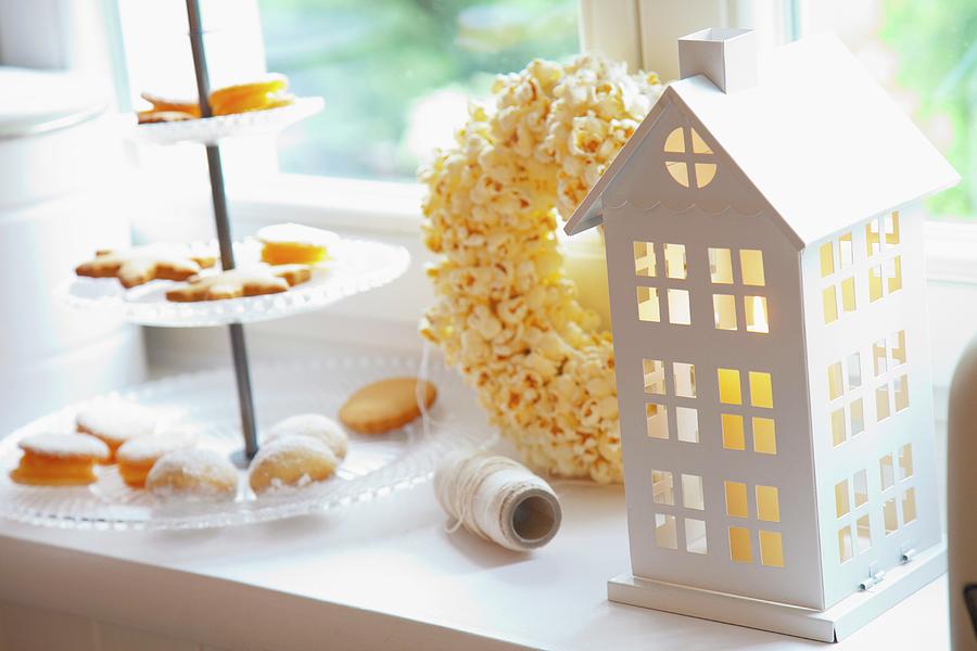 A House-shaped Candle Lantern, A Popcorn Wreath And A Tiered Cake Stand Of Biscuits Photograph by Studio Lipov