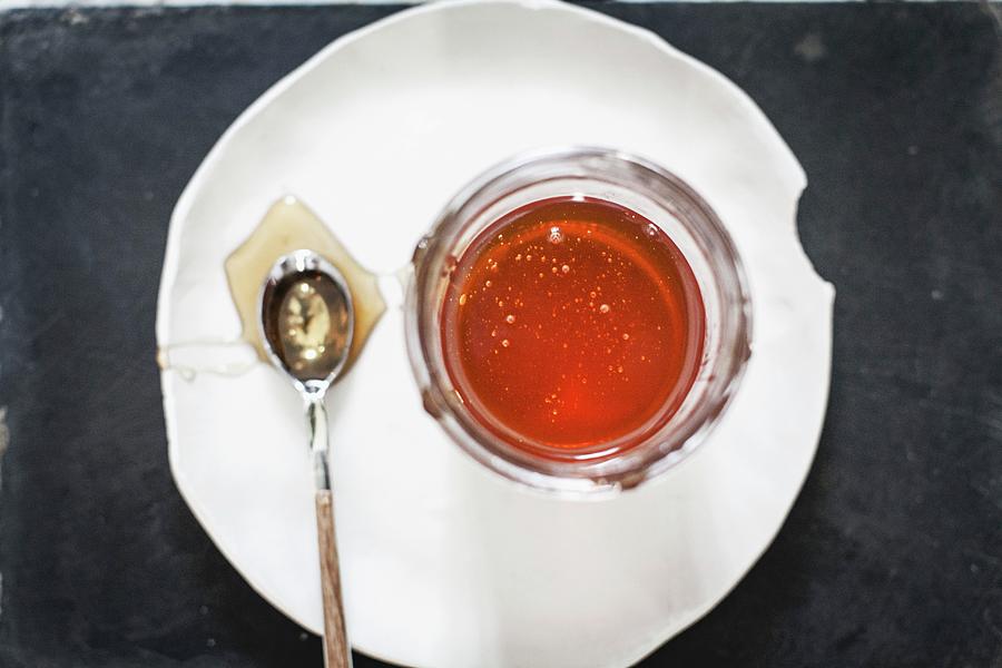 A Jar Of Honey And A Spoon On A Plate Photograph by Alessandra Spairani