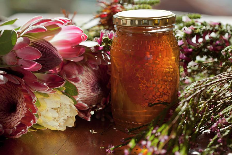 A Jar Of Honey With Honeycomb, Surrounded By Flowers Photograph by Creative Photo Services