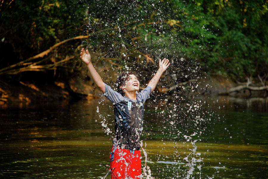 Summer Photograph - A Joyful Boy Playing In River Flings Water Drops High Into The Air by Cavan Images