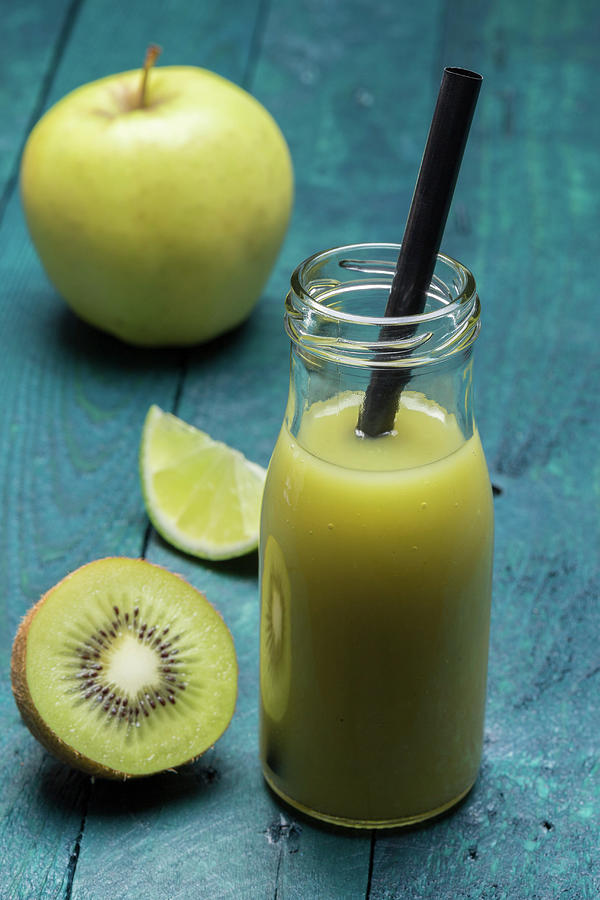 A Kiwi And Apple Smoothie With Lime In A Bottle With A Straw Photograph by Nils Melzer