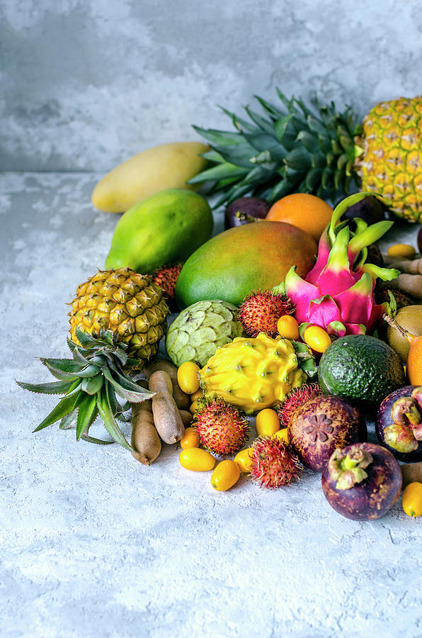 A Large Pile Of Assorted Fresh And Tasty Tropical Fruits On A Gray Background Photograph by Gorobina
