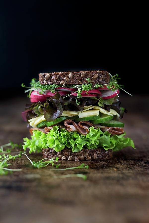 A Large Sandwich With Lettuce, Ham, Cheese, Cucumber, Radishes And Cress On Wholemeal Bread Photograph by Malgorzata Laniak