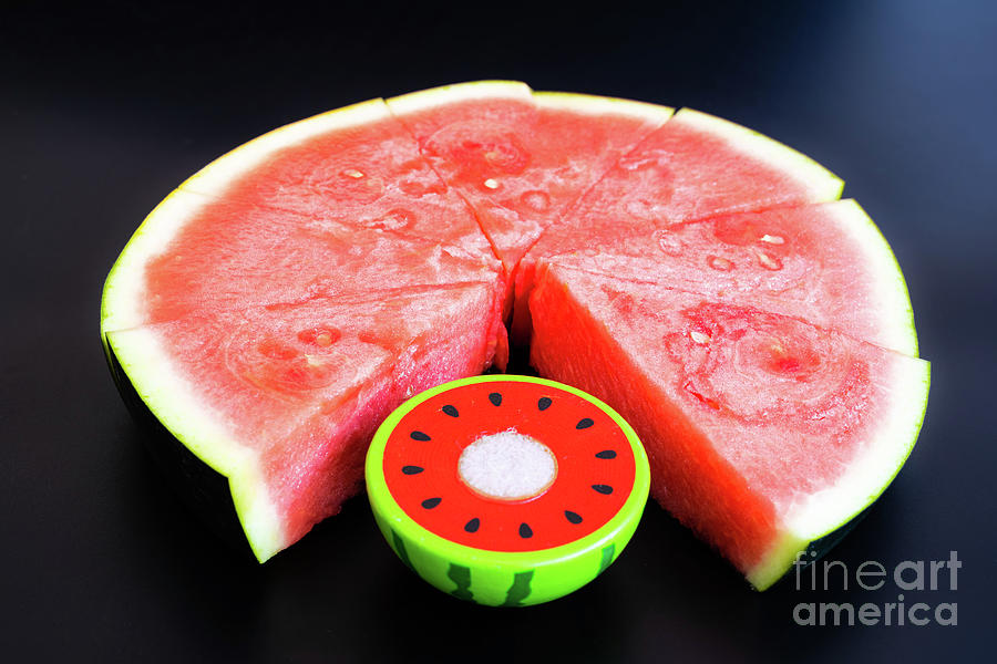 A large slice of watermelon divided into smaller pieces next to  Photograph by Joaquin Corbalan