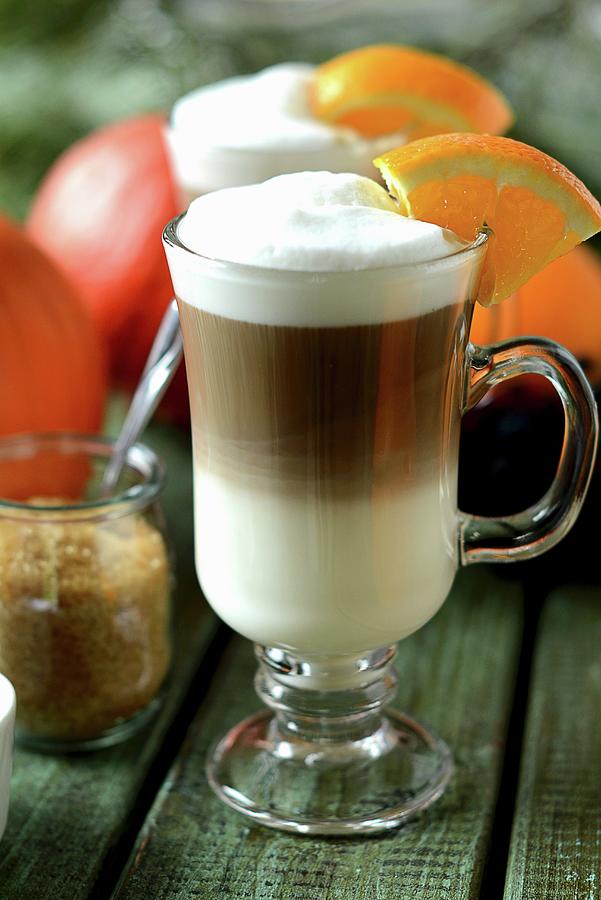 Coffee Photograph - A Latte Macchiato In A Glass Cup Decorated With A Slice Of Orange by Dorota Piekarska