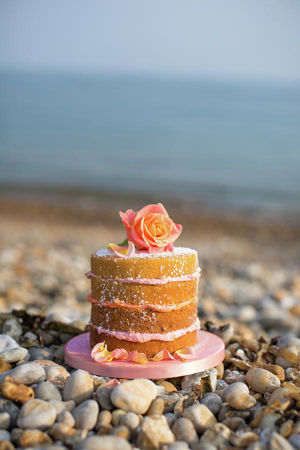 A Layered Cake Decorated With A Rose On A Beach Photograph by Lara Jane Thorpe