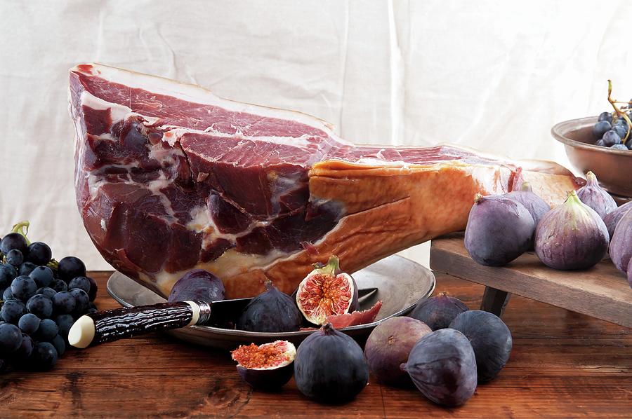A Leg Of Parma Ham, Figs And Blue Grapes Photograph by Atelier Hmmerle