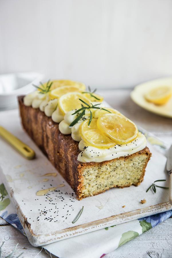 A Lemon And Poppy Seed Loaf With Cream Cheese Frosting And Rosemary Syrup, With A Slice Removed Photograph by Magdalena Hendey