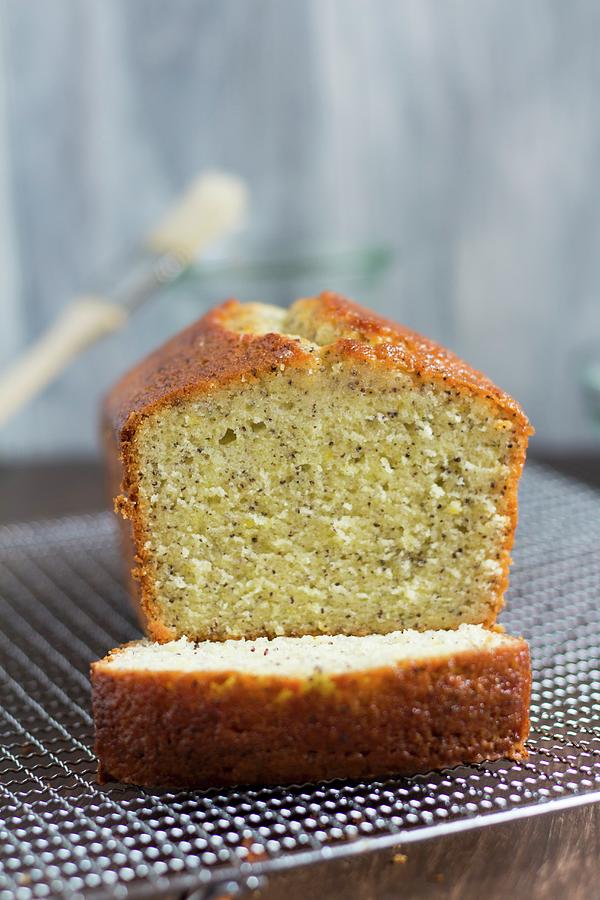 A Lemon And Poppyseed Loaf Cake On A Wire Cooling Rack with One Slice Cut Off Photograph by Kevin Buch