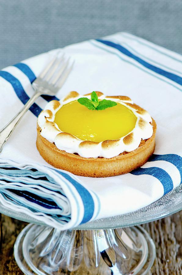 A Lemon Meringue Tartlet On A Cake Stand Photograph by Jamie Watson