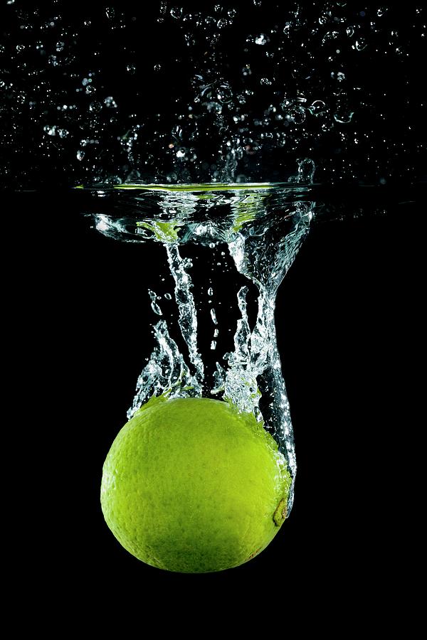 A Lime Falling Into Water With A Splash Photograph by Tom Regester