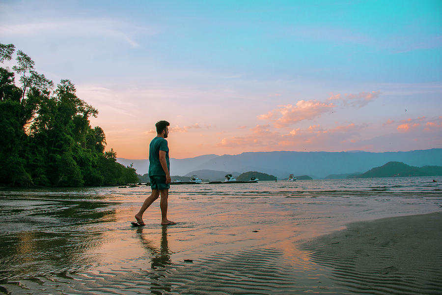 A Man Walking Along The Shore Of The Beach At Sunset Photograph By