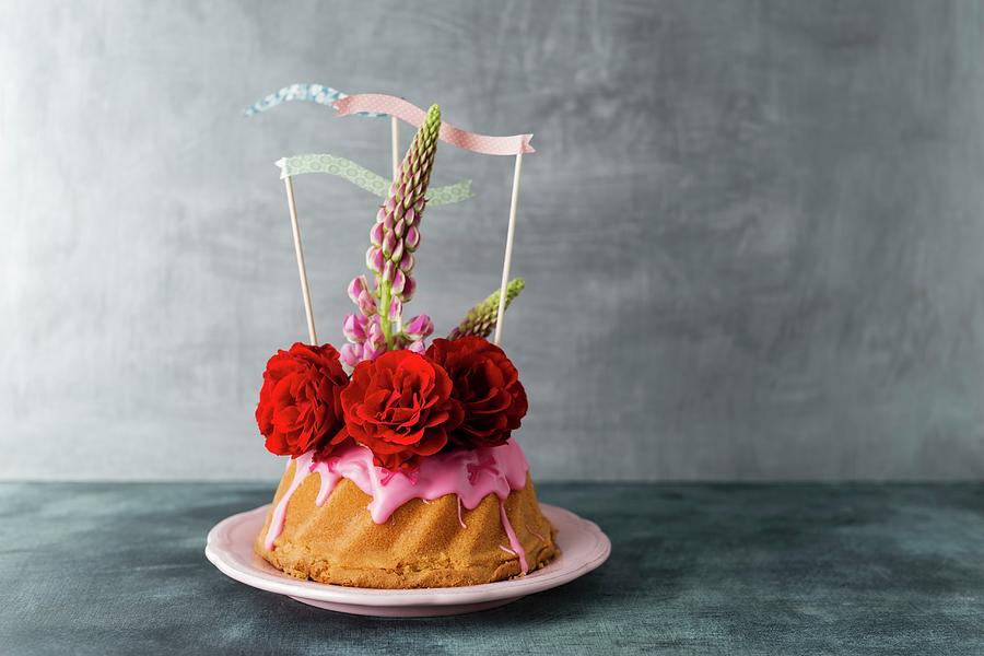 A Mini Bundt Cake Decorated With Icing, Roses, Lupin Flowers And Paper Flags Photograph by Mandy Reschke