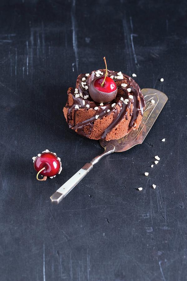 A Mini Cakes With Chocolate Glaze, Almonds And Chocolate-coated Cherries Photograph by Mandy Reschke