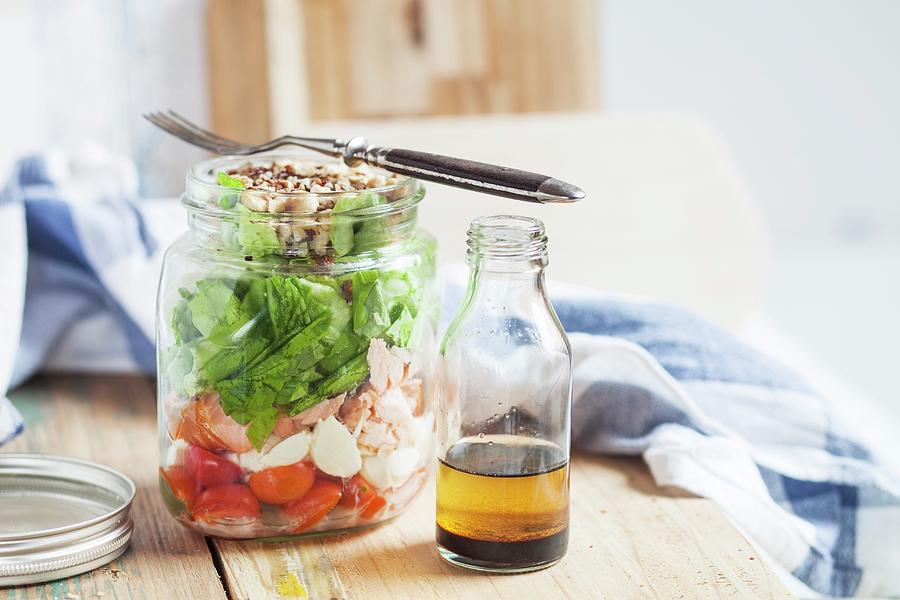 A Mixed Salad With Plum Tomatoes, Mozzarella Balls, Salmon, Lettuce And Toasted Hazelnuts, With A Balsamic And Hazelnut Oil Dressing In A Glass Jar Photograph by Susan Brooks-dammann