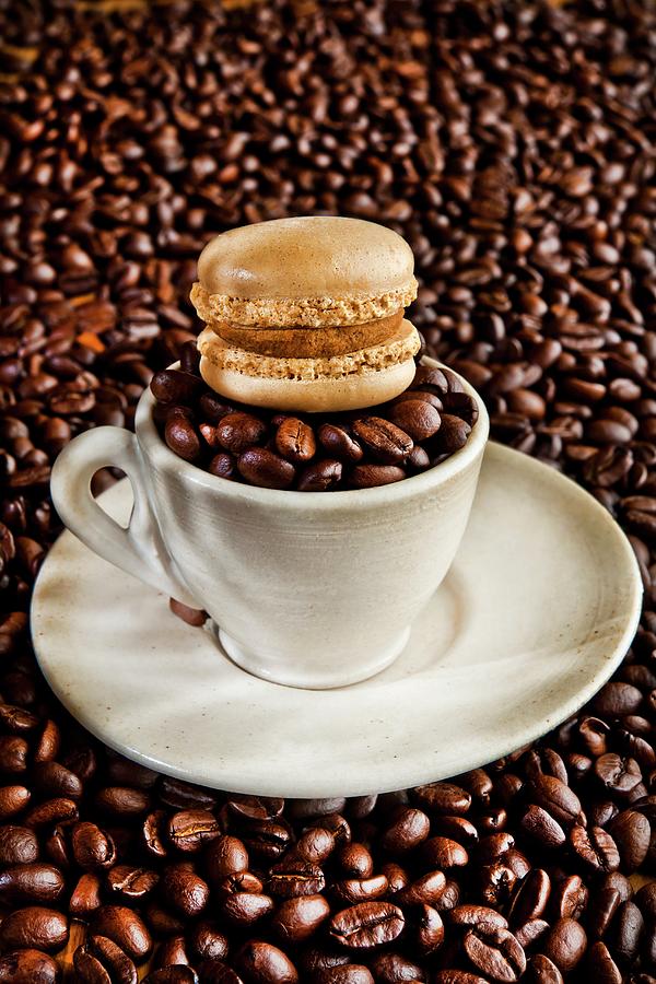 A Mocha Macaroon On Top Of A Cup Filled With Coffee Beans Photograph by Atelier Hmmerle