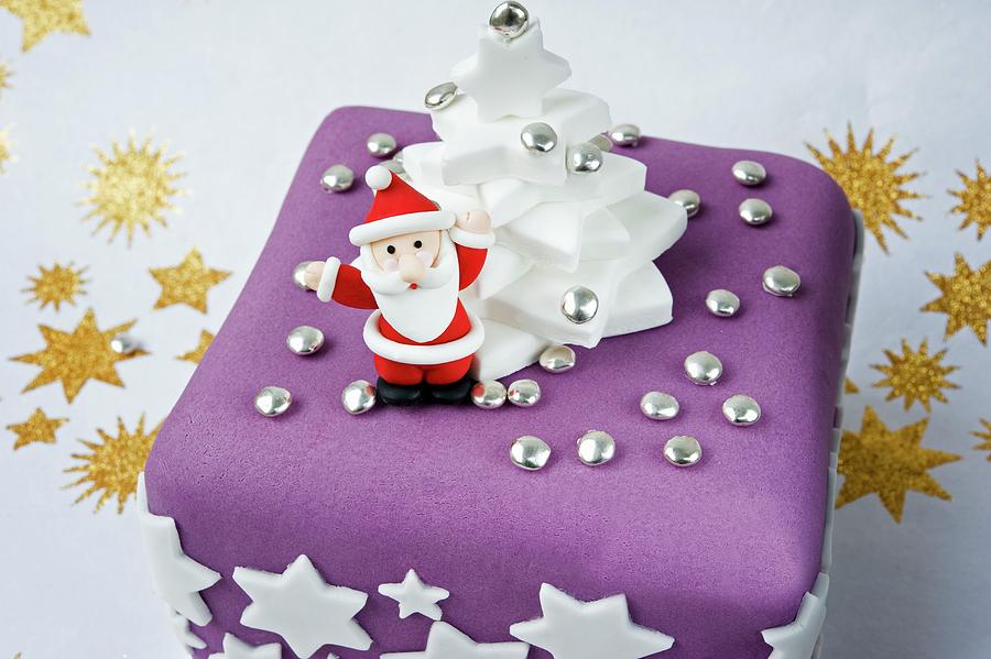 A Model In Icing Of Father Christmas Holding Up His Arms On A Purple ...