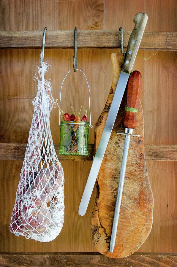 A Net Holding Assorted Types Of Salami, Chillies, A Knife And Board Photograph by Watson, Jamie