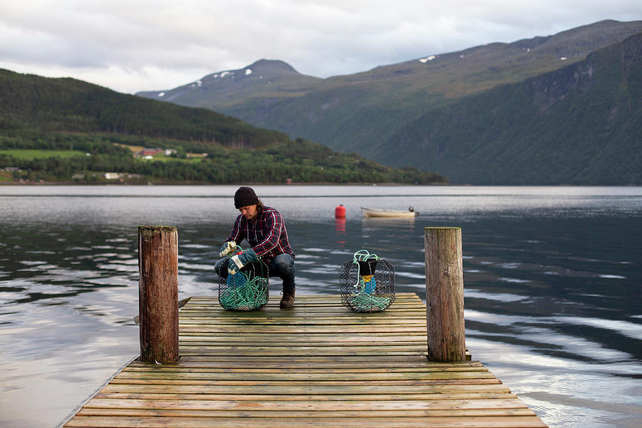 Fish Photograph - A Norwegian Working On Some Crab Pots On A Dock By The Fjord by Cavan Images