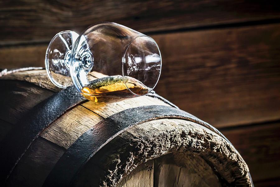 A Overturned Glass Of Cognac On An Old Wooden Barrel Photograph by Shaiith