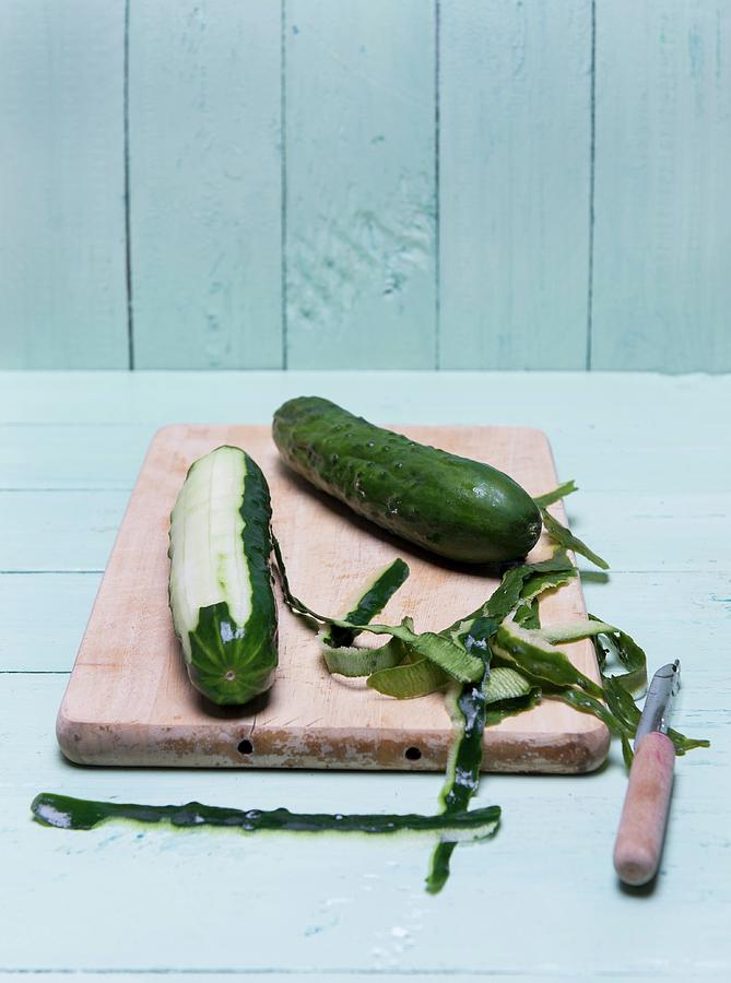 A Peeled Cucumber On A Wooden Board With A Peeler And Peel Photograph by Angelika Grossmann