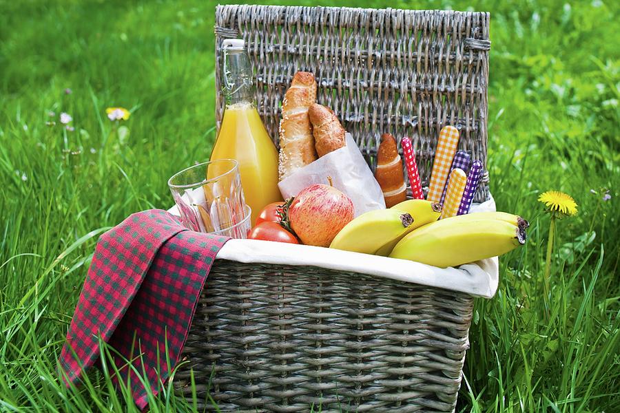 A Picnic Basket Filled With Fruit, Rolls And Orange Juice Photograph by ...