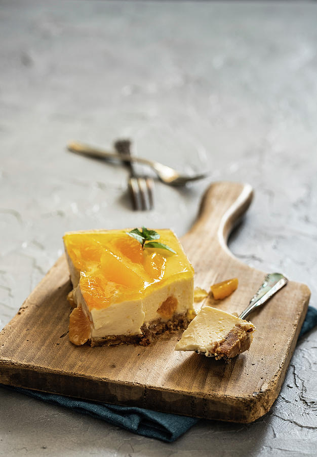 A Piece Of Cheesecake With Mandarins On A Wooden Board Photograph by M. Nlke