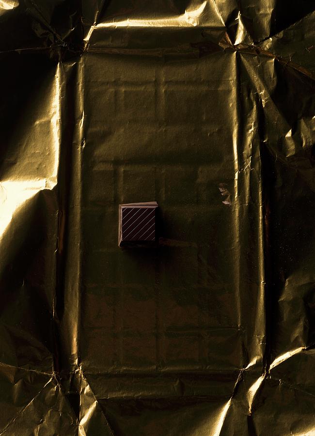 A Piece Of Chocolate On Gold Paper On A Table Photograph by Gaelle Ap