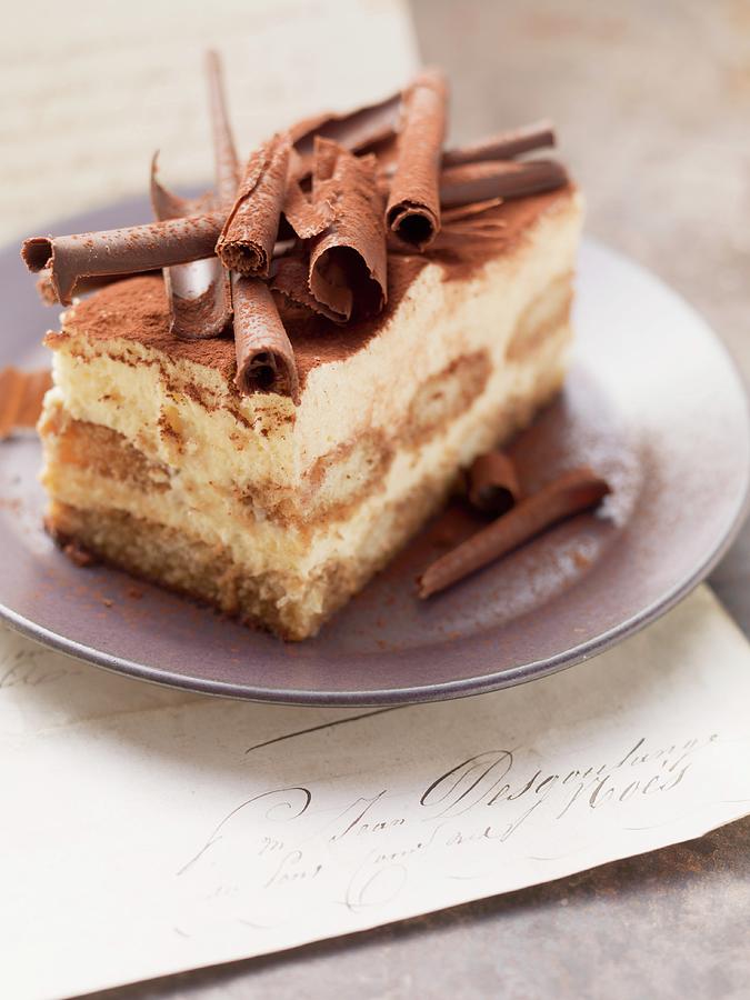 A Piece Of Tiramisu Cake Topped With Rolls Of Chocolate Photograph by Foodcollection