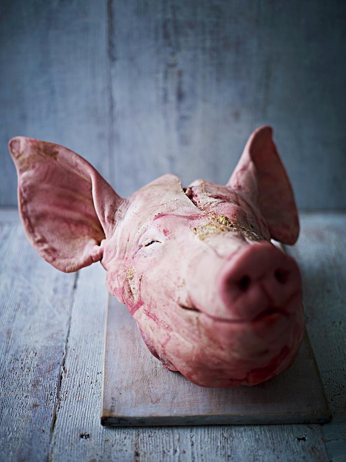 A Pigs Head On A Chopping Board Against A Wooden Board Photograph by Myles New