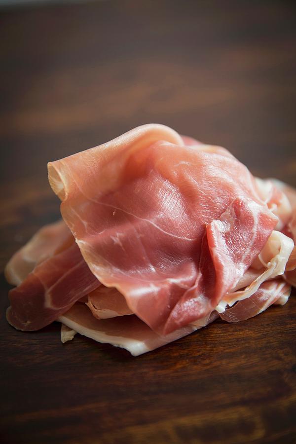A Pile Of Parma Ham Slices On A Wooden Board Photograph by Moe Kafer Photography