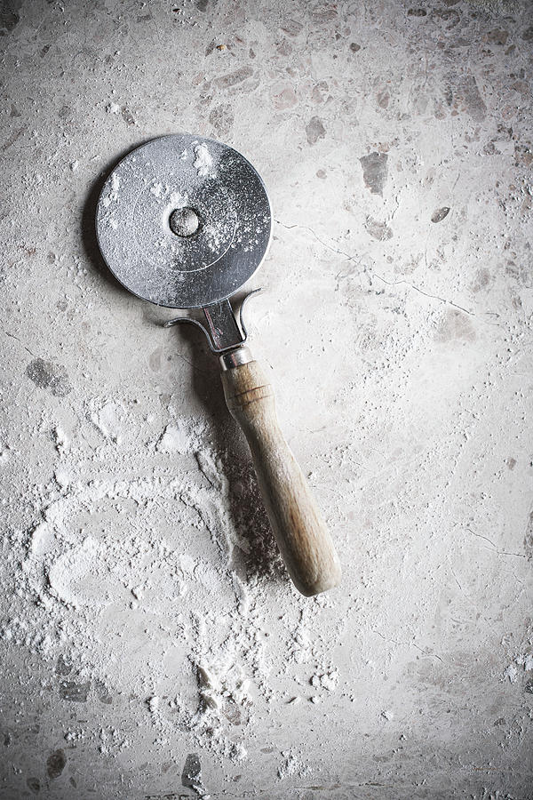 A Pizza Cutter And Flour On A Stone Surface Photograph by Great Stock!