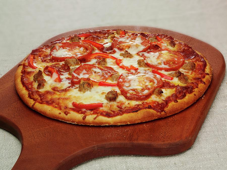 A Pizza Topped With Pepperoni, Pepper And Mozzarella On A Chopping Board Photograph by Albert P Macdonald