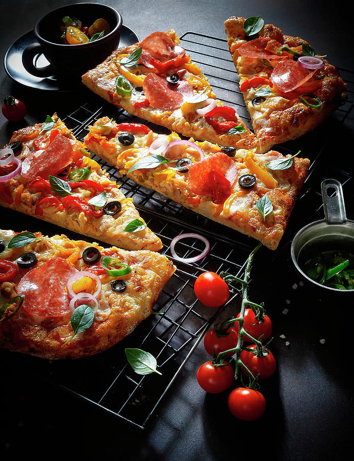 A Pizza Topped With Salami, Tomatoes And Olives; Sliced Photograph by Vadim Piskarev