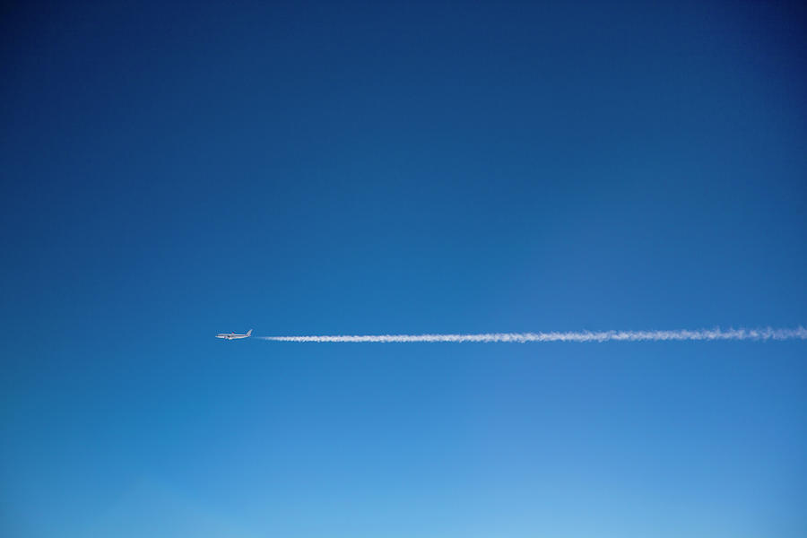 A Plane And Vapor Trails In The Sky Photograph by Tobias Titz