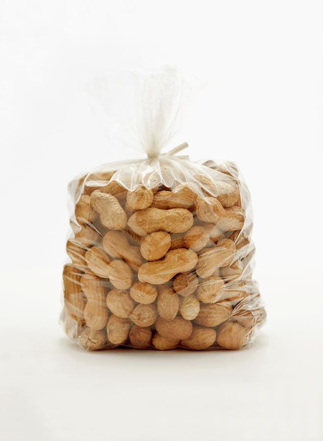 A Plastic Bag Of Peanuts Against A White Background Photograph by William Boch